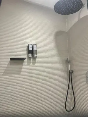 a bathroom with a shower with a hose on the wall at AquaEros - Appart Jacuzzi Carré Eden Marrakech in Marrakech