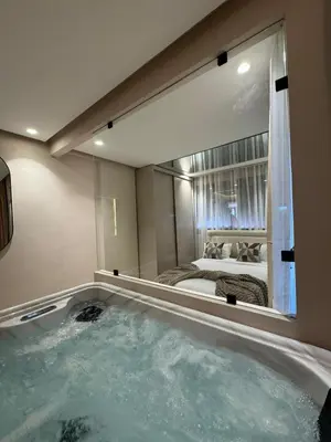 a large bathroom with a tub with a large mirror at AquaEros - Appart Jacuzzi Carré Eden Marrakech in Marrakech