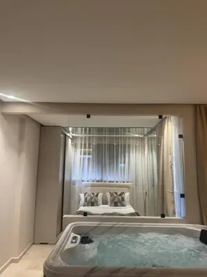 a bathroom with a tub with a bed in a mirror at AquaEros - Appart Jacuzzi Carré Eden Marrakech in Marrakech