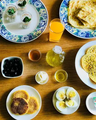 a wooden table with plates of eggs and pancakes at studio chez l'habitant in Marrakech