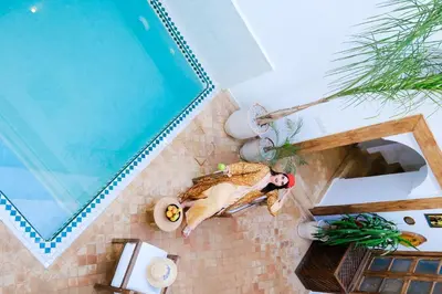 a woman laying on a wall next to a swimming pool at Riad Zellige in Marrakech