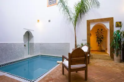 a swimming pool in a room with a chair and a chair at Riad Zellige in Marrakech