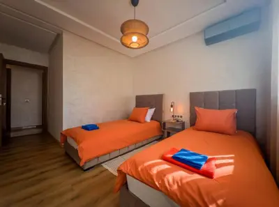 a bedroom with two beds with orange sheets and a light at Appartement Marrakech 2 Chambres De Luxe Orange in Marrakech