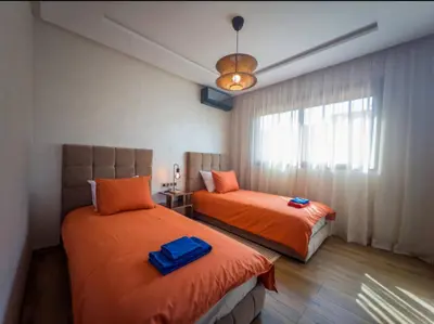a bedroom with two beds with orange sheets and a window at Appartement Marrakech 2 Chambres De Luxe Orange in Marrakech