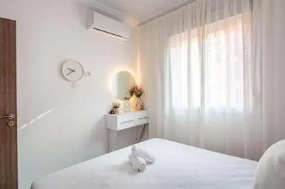 a white bedroom with a bed and a mirror at Luxueux appartement in Marrakech