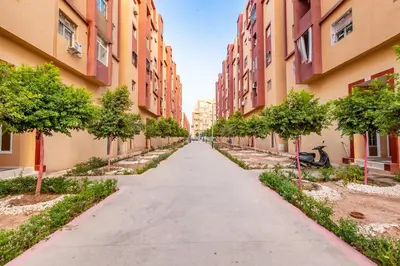 an empty alley between two tall buildings with trees at Luxueux appartement in Marrakech