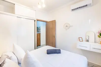 a white bedroom with a bed and a mirror at Luxueux appartement in Marrakech
