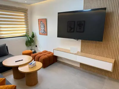 a living room with a couch and a tv on a wall at T3 élégant 2ch piscine chauffée & fitness in Marrakech