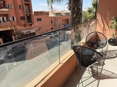 a balcony with two chairs and a view of a street at T3 élégant 2ch piscine chauffée & fitness in Marrakech