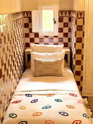 a bed in a small room with a pillow on it at Riad El Badun in Marrakech