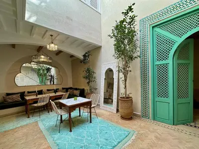 a dining room with a table and a green door at Riad El Badun in Marrakech