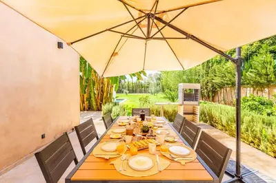 a wooden table with an umbrella on a patio at Villa Amelkis avec Piscine - 4 suites de luxe à Marrakech in Marrakech