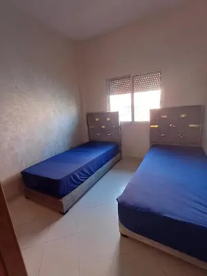 two beds in a room with blue sheets at Tachfine appartement in Marrakech