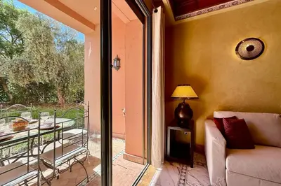 a living room with a couch and a glass door to a balcony at Two Bedroom Garden Apartment in Palmeraie 2 in Marrakech