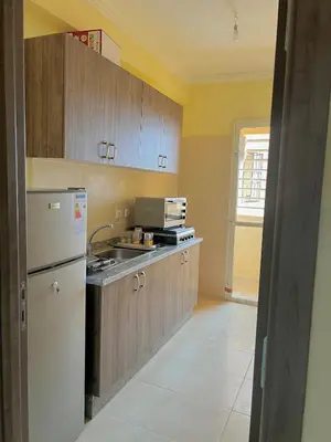 a kitchen with wooden cabinets and a white refrigerator at Apartment 5 minutes from the airport in Marrakech