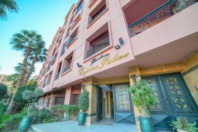 a pink building with a door and palm trees at Royal Pool Apartment Hivernage Marrakech in Marrakech