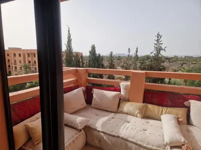 a couch sitting on top of a balcony at Appartement 2 chambres, piscine, vue palmeraie in Marrakech
