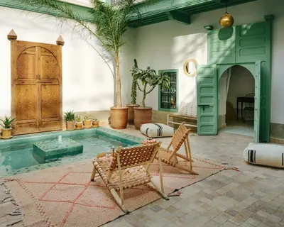 a patio with a pool with two chairs and a table at Riad dar Maloukti in Marrakech