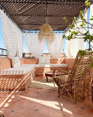 a pergola with a couch and chairs on a patio at Riad dar Maloukti in Marrakech