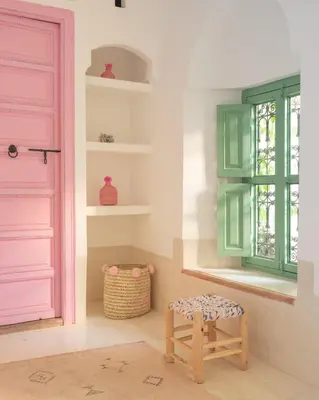 a room with a pink door and a stool at Riad dar Maloukti in Marrakech