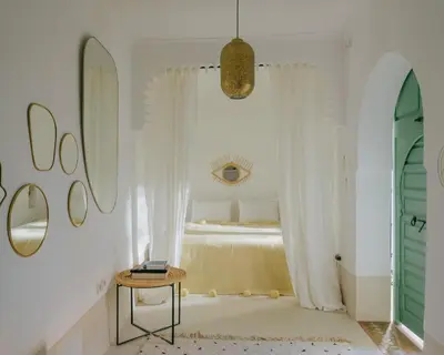 a bedroom with a bed and a table and a mirror at Riad dar Maloukti in Marrakech