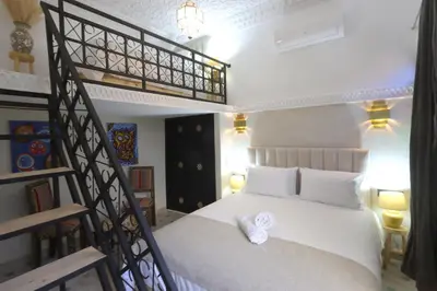 a bedroom with a white bed and a spiral staircase at riad NAMLA in Marrakech