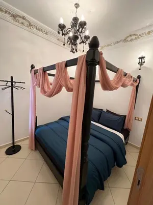 a bedroom with a bed with pink curtains and a cross at إقامة المنتزه الجديد حدا مرجان طريق كازا في مراكش in Marrakech