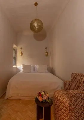 a bedroom with a bed and a table with flowers on it at Riad Cedrat in Marrakech