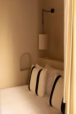 a bedroom with a bed with white pillows and a lamp at Riad Cedrat in Marrakech