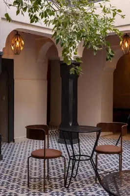 a table and two chairs in a room with a tree at Riad Cedrat in Marrakech