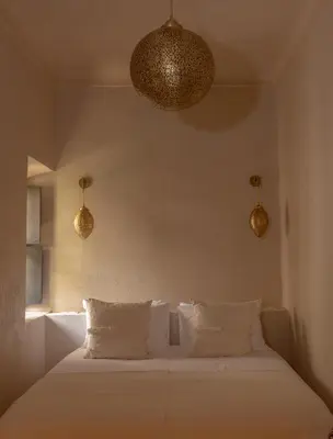 a bedroom with a white bed with three pillows at Riad Cedrat in Marrakech