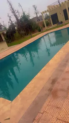 a swimming pool in front of a house at villa BASMA in Marrakech