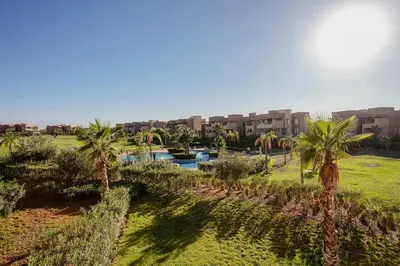 a view of a park with palm trees and a building at Your Tiny Paradise - Marrakech - Prestigia in Marrakech