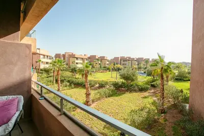 a balcony with a view of a park with palm trees at The Art of Stay - Marrakech - Prestigia in Marrakech