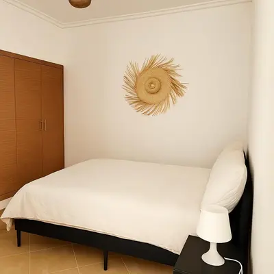 a white bedroom with a bed and a lamp at Cosy appartement 75m2 in Marrakech