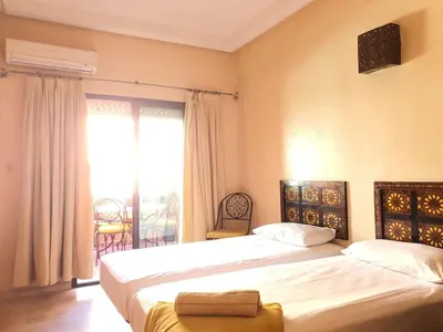 a bedroom with two beds and a large window at Appartememt Hivernage 4 in Marrakech