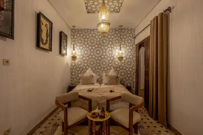a bedroom with a bed and two chairs and a table at Riad Musee in Marrakech