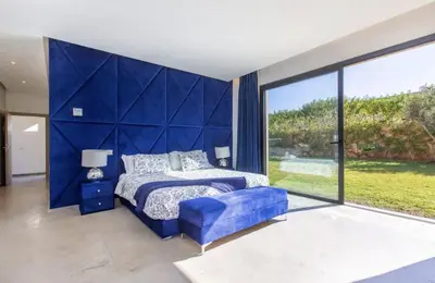 a bedroom with a blue bed and a large window at Villa Atlas piscine chauffee sans vis a vis in Marrakech