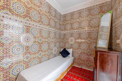 a bedroom with a bed in a room with wallpaper at Dar Tbib in Marrakech