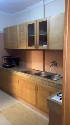 a kitchen with wooden cabinets and a sink at Appartement Marrakech gueliz climatisé avec piscine et baby foot in Marrakech
