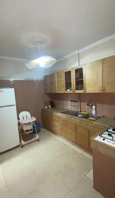a kitchen with wooden cabinets and a white refrigerator at Appartement Marrakech gueliz climatisé avec piscine et baby foot in Marrakech