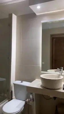a bathroom with a sink and a toilet and a mirror at Appartement Marrakech gueliz climatisé avec piscine et baby foot in Marrakech