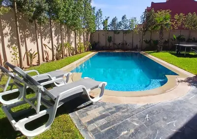 a swimming pool with two lounge chairs next to a fence at Villa Élégance Familiale in Marrakech