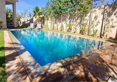 a swimming pool in front of a house at Villa Élégance Familiale in Marrakech