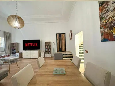 a living room with a table and a television at Duplex Majorelle avec Jardin et Parking in Marrakech
