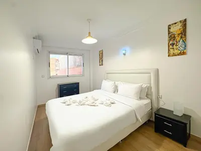 a bedroom with a large white bed and a window at Duplex Majorelle avec Jardin et Parking in Marrakech