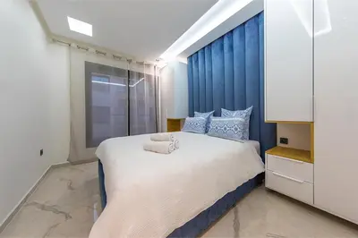 a bedroom with a large bed with blue curtains at Chic & comfort in the heart of Marrakech train station in Marrakech