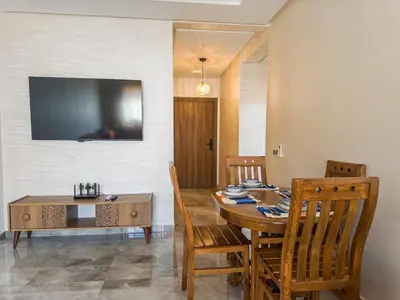 a dining room with a table and chairs and a television at Modern & cozy 2 bedroom apartment in Marrakech