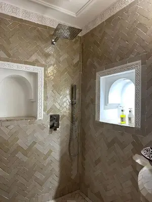 a bathroom with a shower with a tile wall at Riad Le Bijou de Zahra Marrakech Kasbah in Marrakech