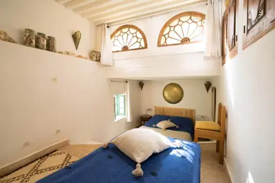 two beds in a room with two windows at Dar Kleta in Marrakech